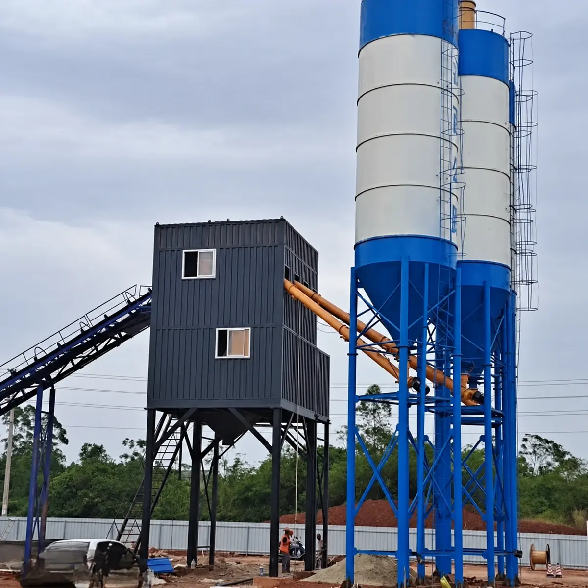 Real shot of enclosed batching plant main building packaging, three vertical powder silo, and conveyor belt